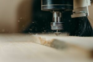 Home CNC machine in action, precisely cutting a wooden panel with sawdust flying.