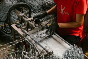 A person in a workshop uses a wire bending machine, highlighting craftsmanship and industry.